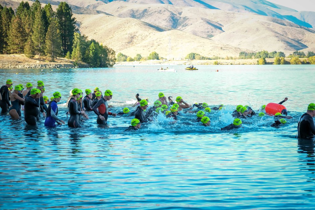 3,800m Swimmers diving in at the start of the race with safety jet ski and kayak nearby and the Benmore range in the background.
