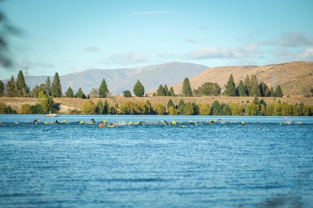 1500m swimmers swimming the race from a distance with a Jetski near by the opposite shore in the background
